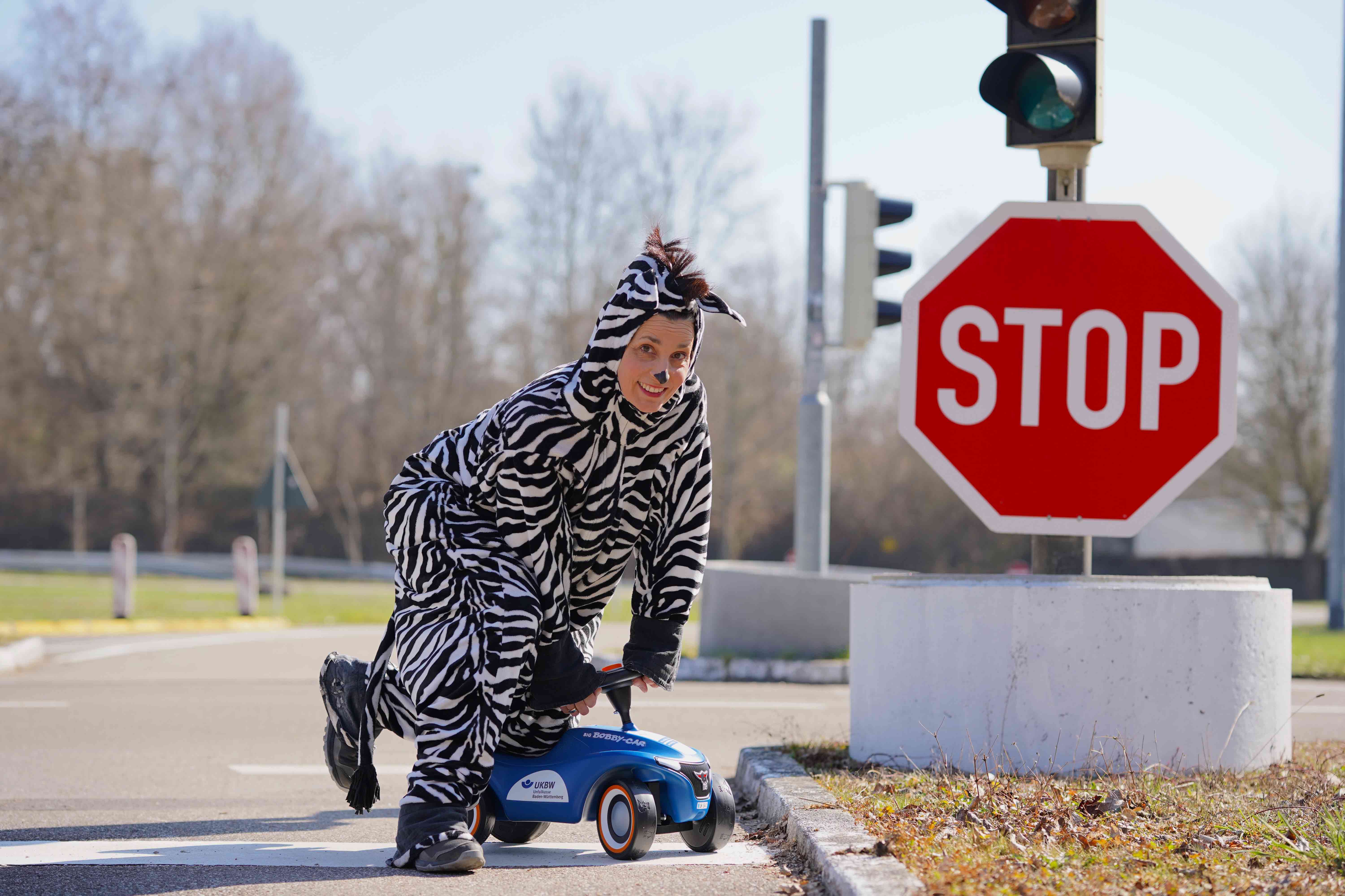 Eine Person in einem Zebra-Kostüm steht im Freien neben einem roten Stoppschild.