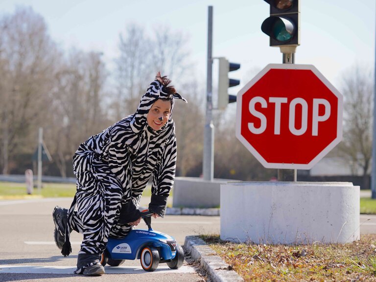Eine Person in einem Zebra-Kostüm steht im Freien neben einem roten Stoppschild.