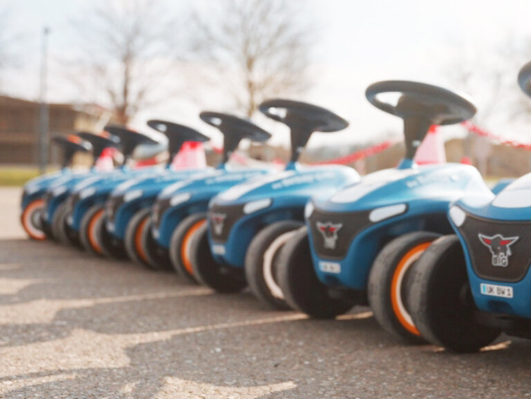 mehrere blaue Rutschauto stehen nebeneinander auf einem asphaltierten Platz.